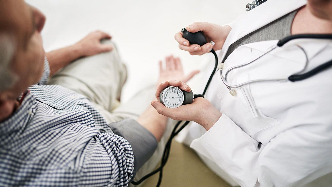 A cardiologist measures the blood pressure of a patient with signs of hypertension